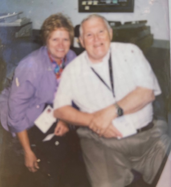A grainy photo of Cheryl Wood in a purple shirt with short hair and Bob Wood in a white button up.