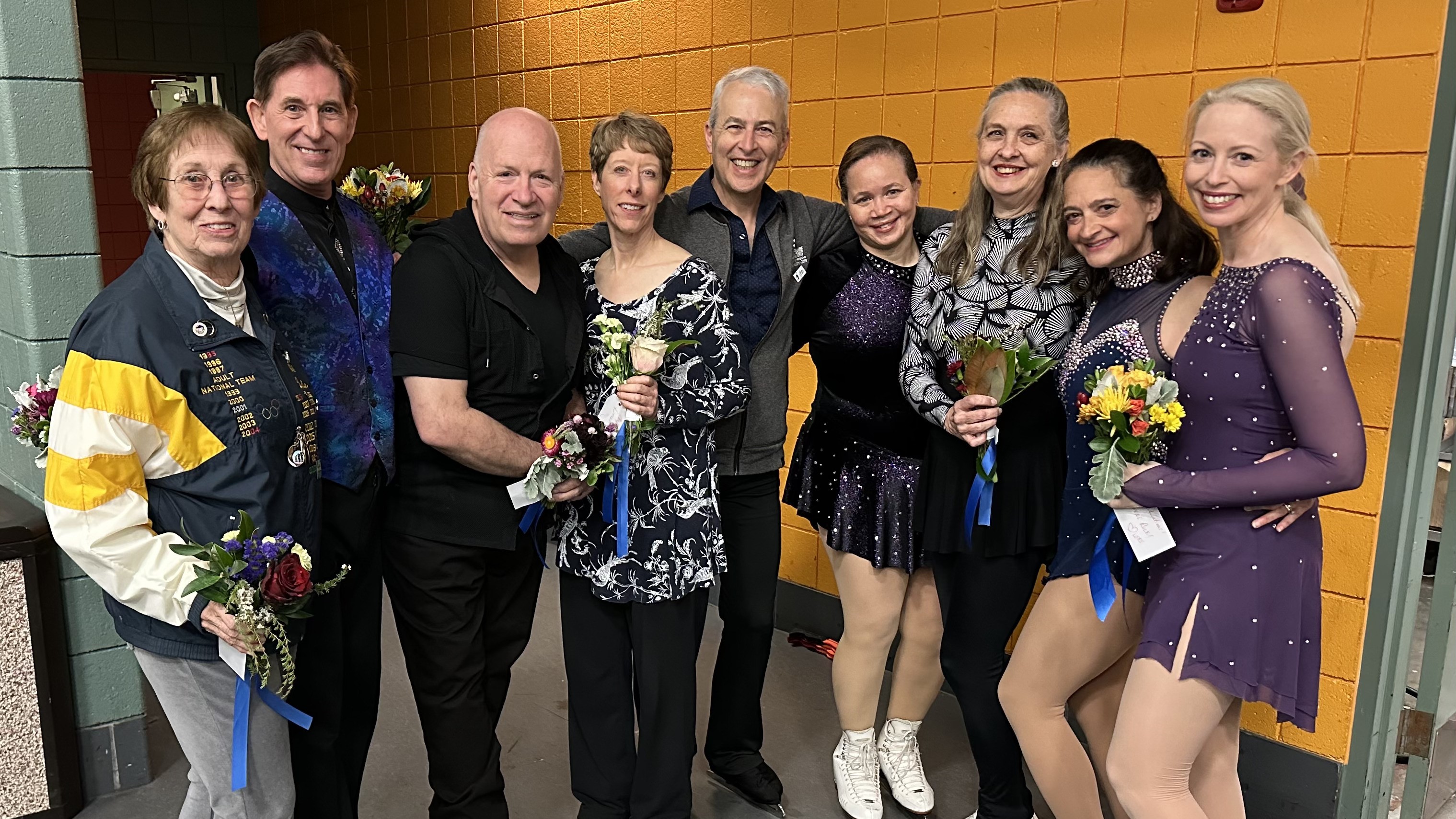 lifers pose for a photo. They are wearing either normal clothes or skating costumes