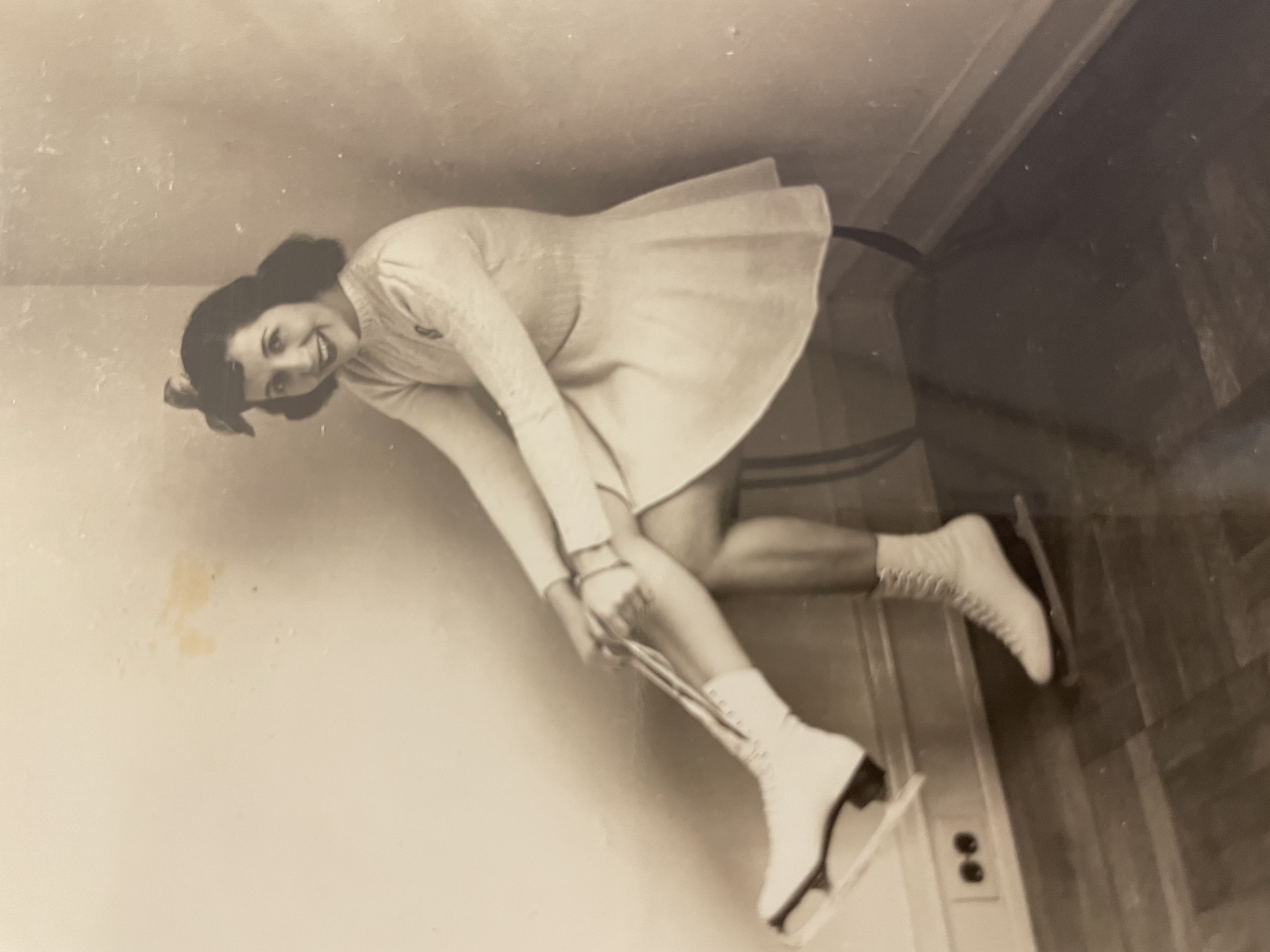 Berda Weisman ties her skates while smiling at the camera.