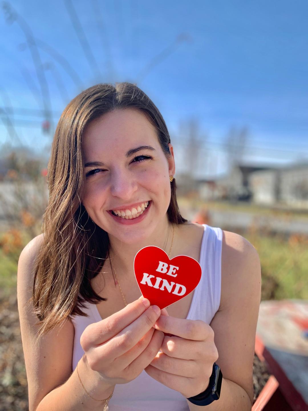 Angela Martino holds up a small heart that says "be kind." 