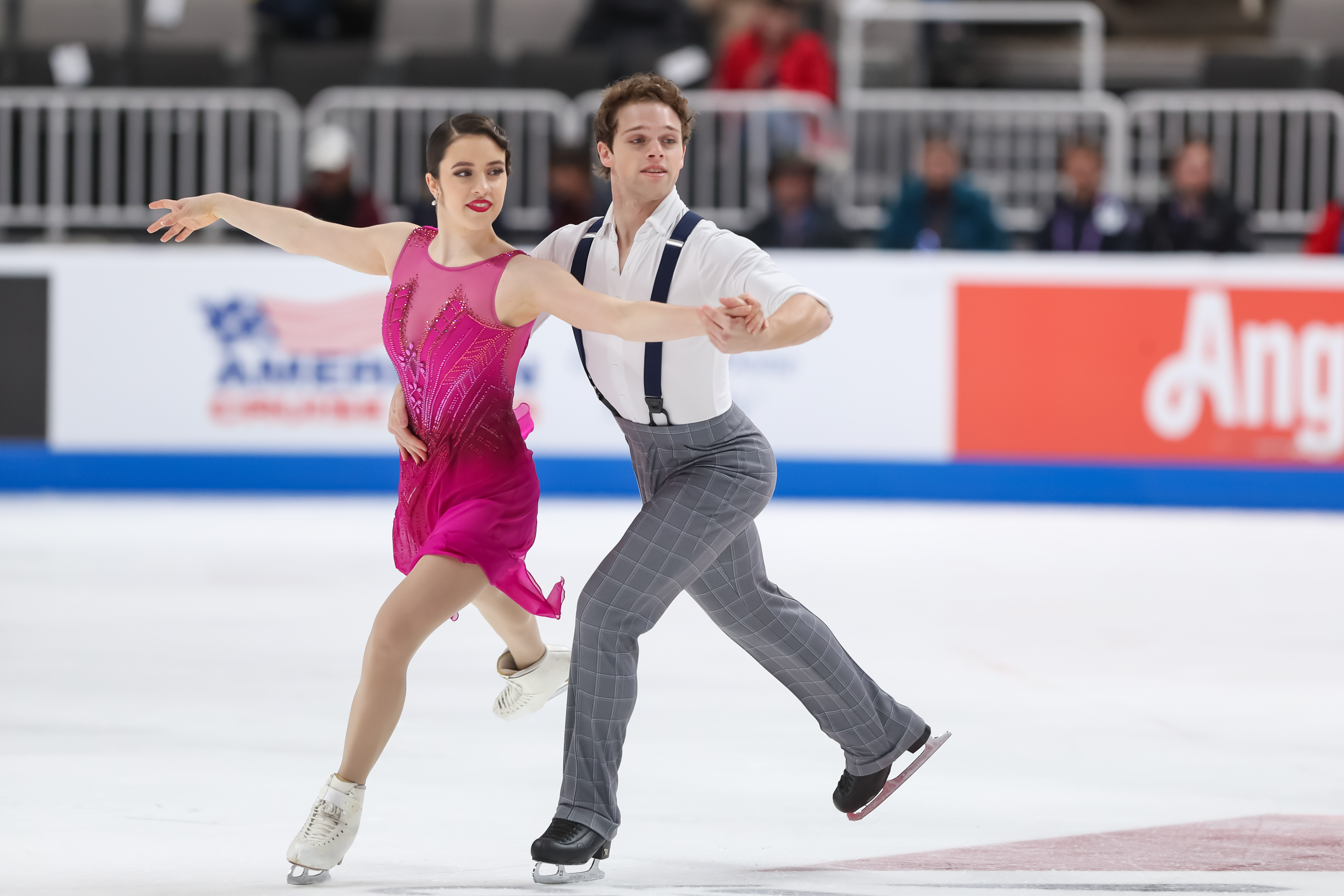 Caroline Green and Michael Parsons compete at the 2023 Toyota U.S. Championships. Caroline is wearing a pink dress amd Michael is wearing a white shirt with suspenders and dark pants 
