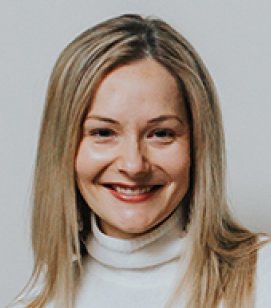 Headshot of Emily Hollander. Emily is a woman with shoulder length blonde hair wearing a white turtleneck sweater