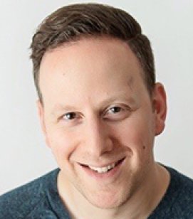 Headshot of Josh Fischel. Josh is a man with short brown hair wearing a dark blue tshirt