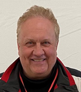 Headshot of Lee Cabell. Lee is an older man with short blonde hair wearing a red, white and blue jacket