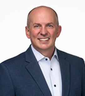 Headshot of Matt Farrell. Matt is an older white man wearing a white button up shirt with a navy blue blazer. 