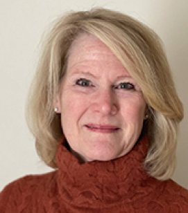 Headshot of Peggy Graham. Peggy is an older woman with shoulder length blonde hair wearing a red turtleneck sweater