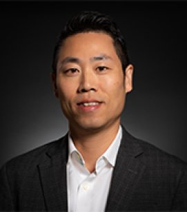 Headshot of William Tran. William is an Asian man with short black hair wearing a white buttondown shirt with a black blazer over top